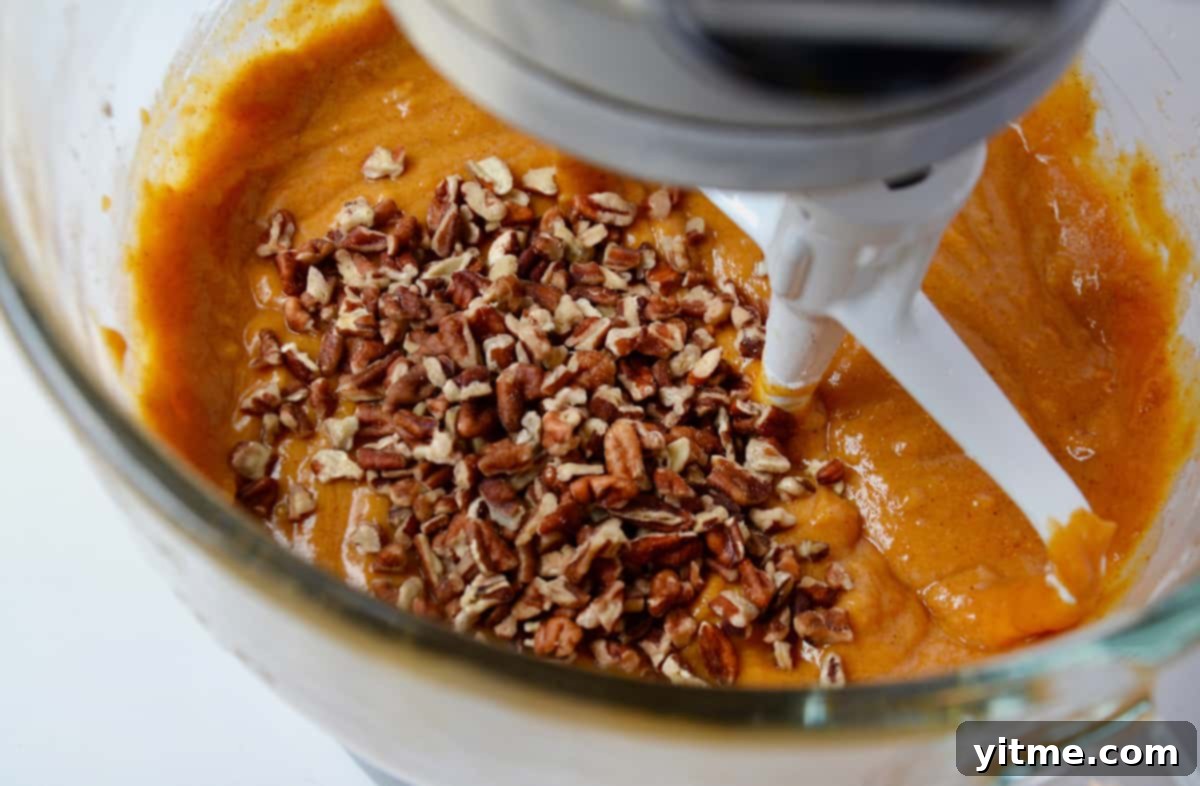 Pumpkin bar batter with pecans in a stand mixer bowl.