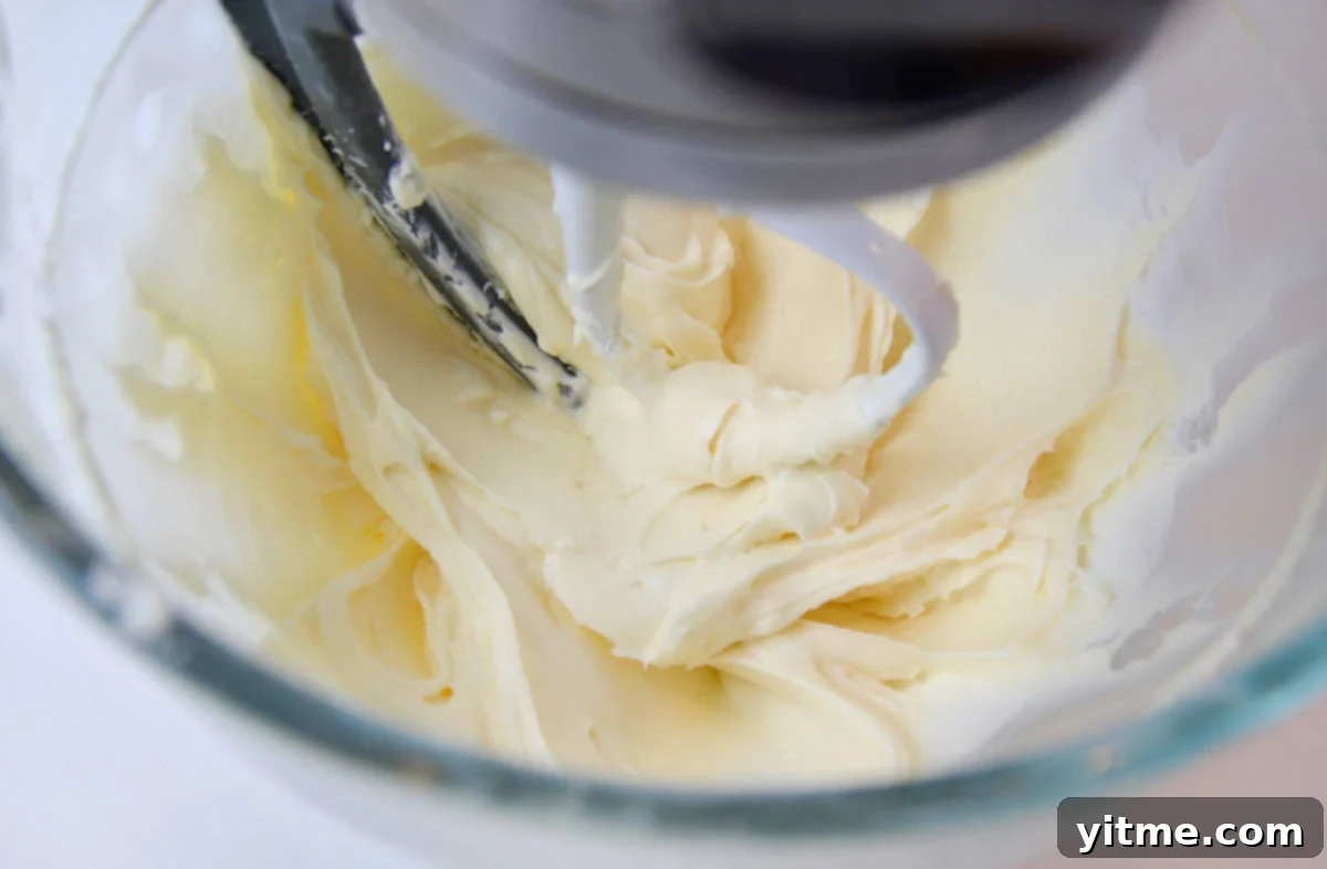 Cream cheese frosting being mixed in a stand mixer.