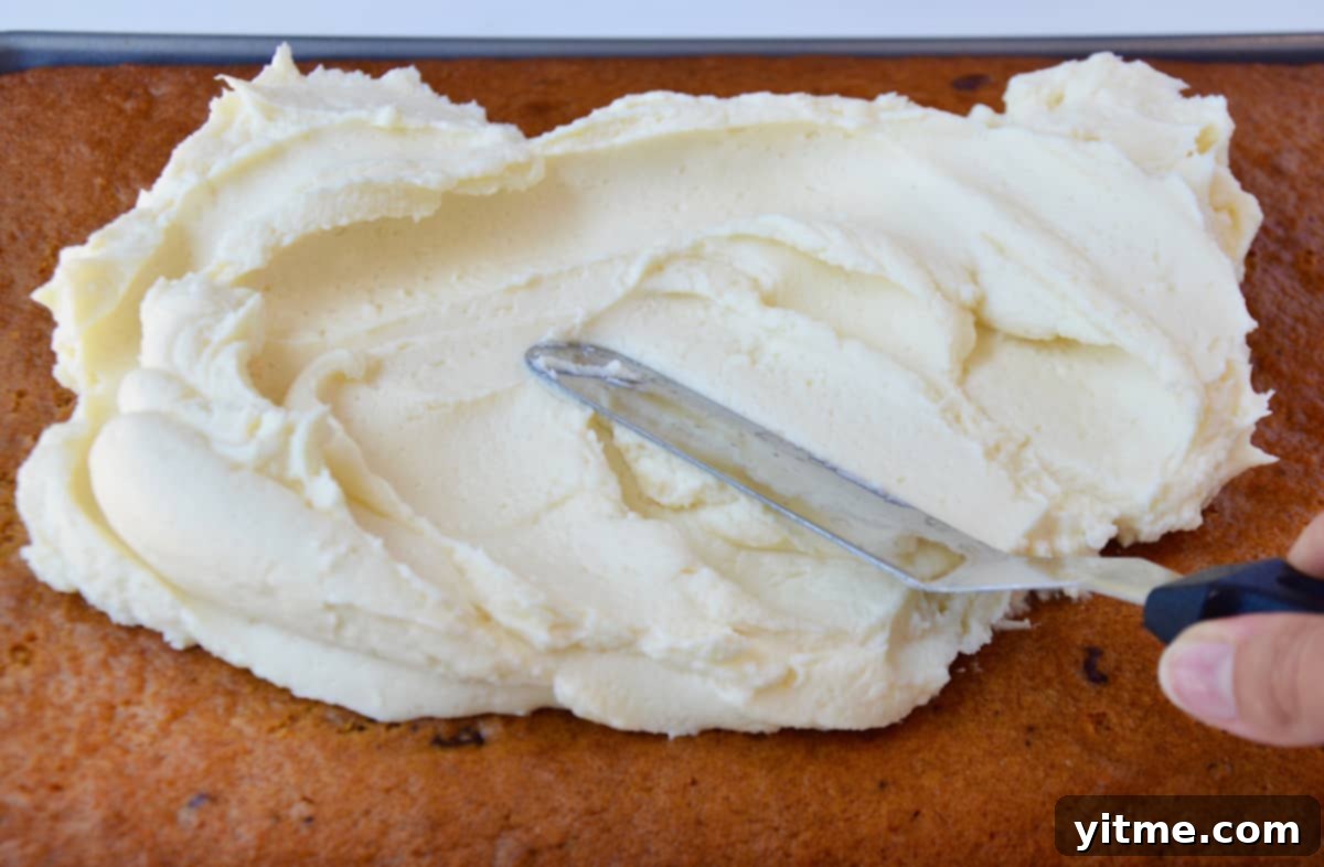 Spreading cream cheese frosting on pumpkin bars.