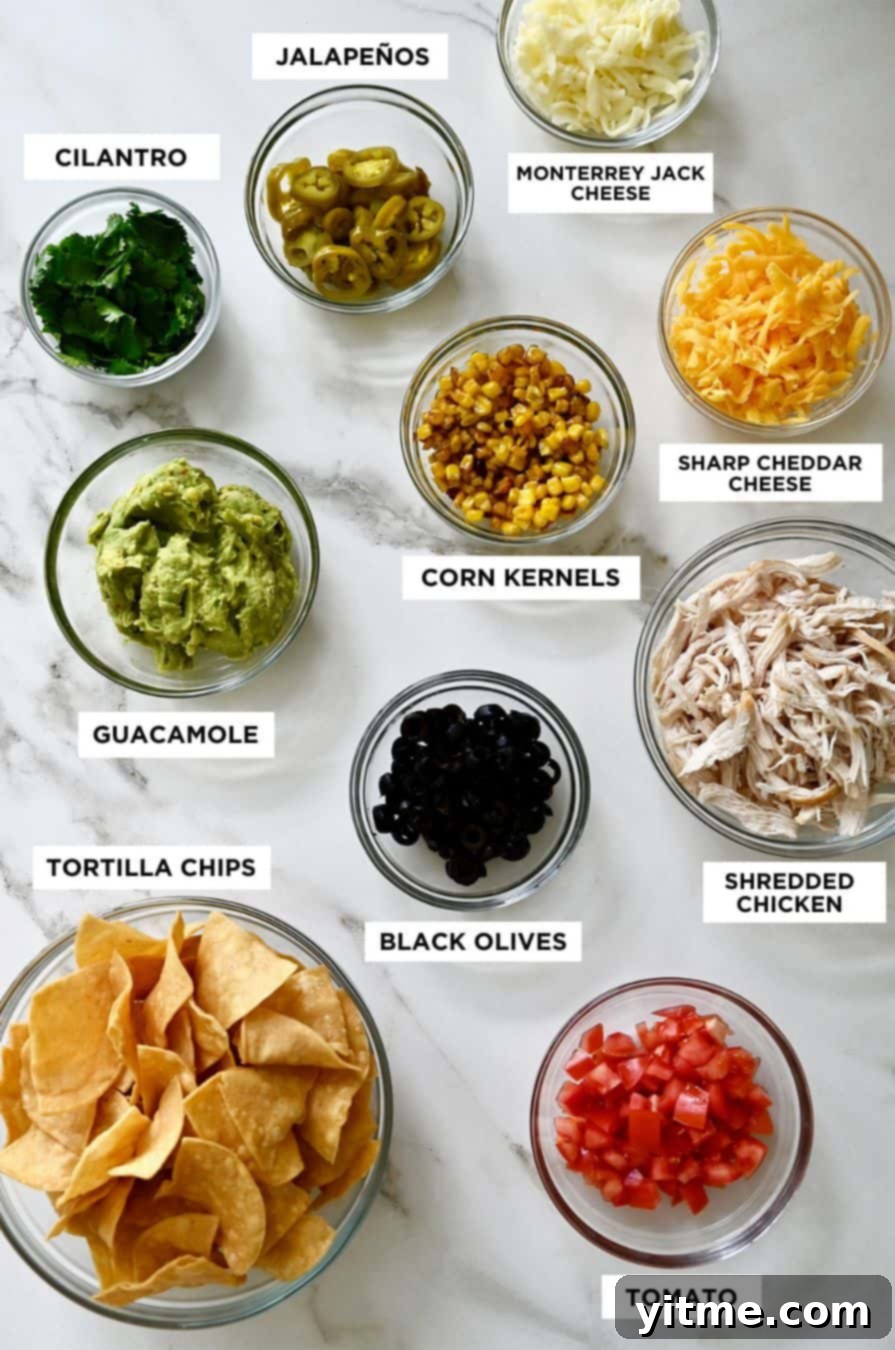 Bowls containing ingredients and labels for nachos, including tortilla chips, guacamole, cilantro, jalapeños, shredded cheese, corn kernels and shredded chicken.