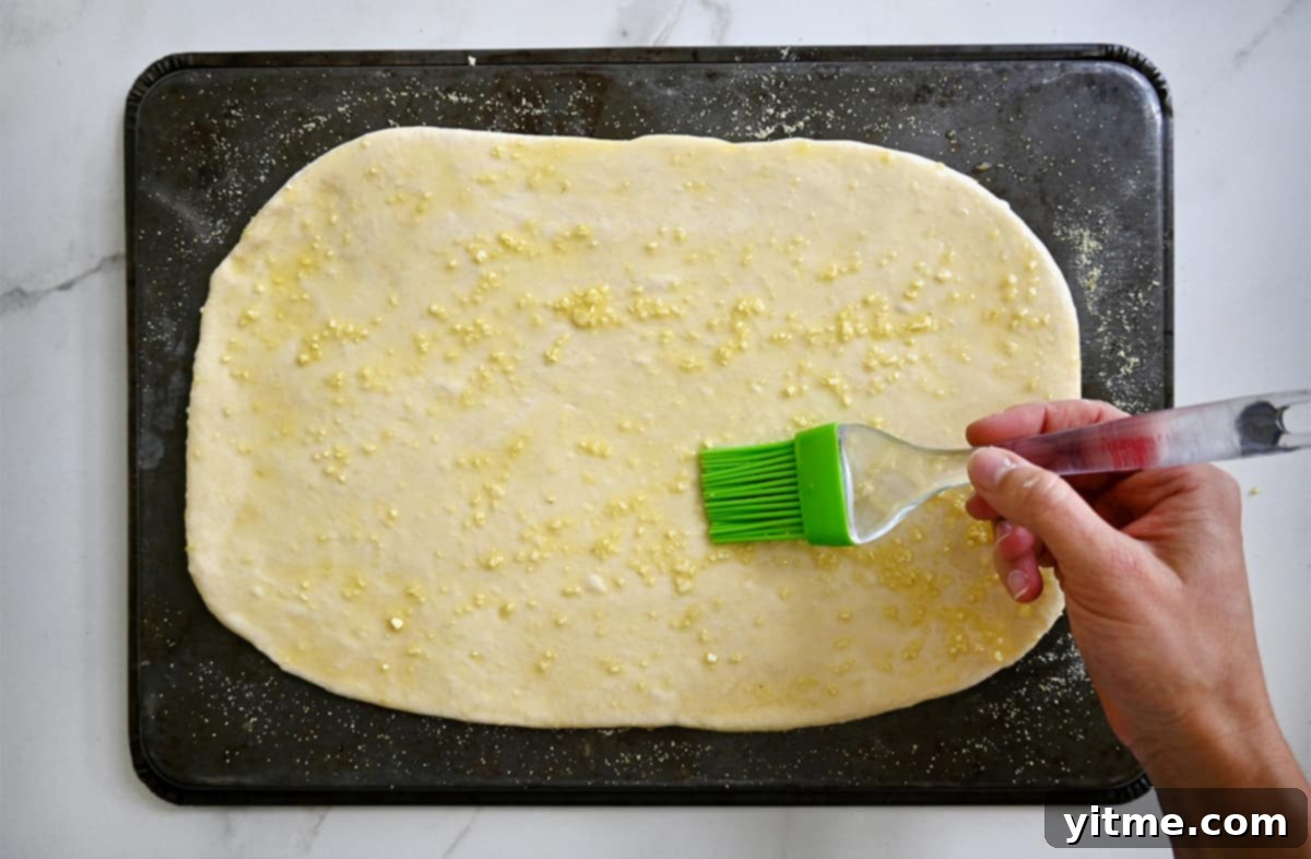 Spreading garlic-infused olive oil on pizza dough