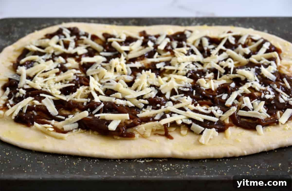 Pizza dough topped with caramelized onions and shredded Gruyere cheese