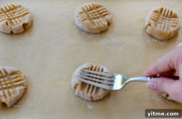 Hand with fork pressing down on peanut butter cookie dough