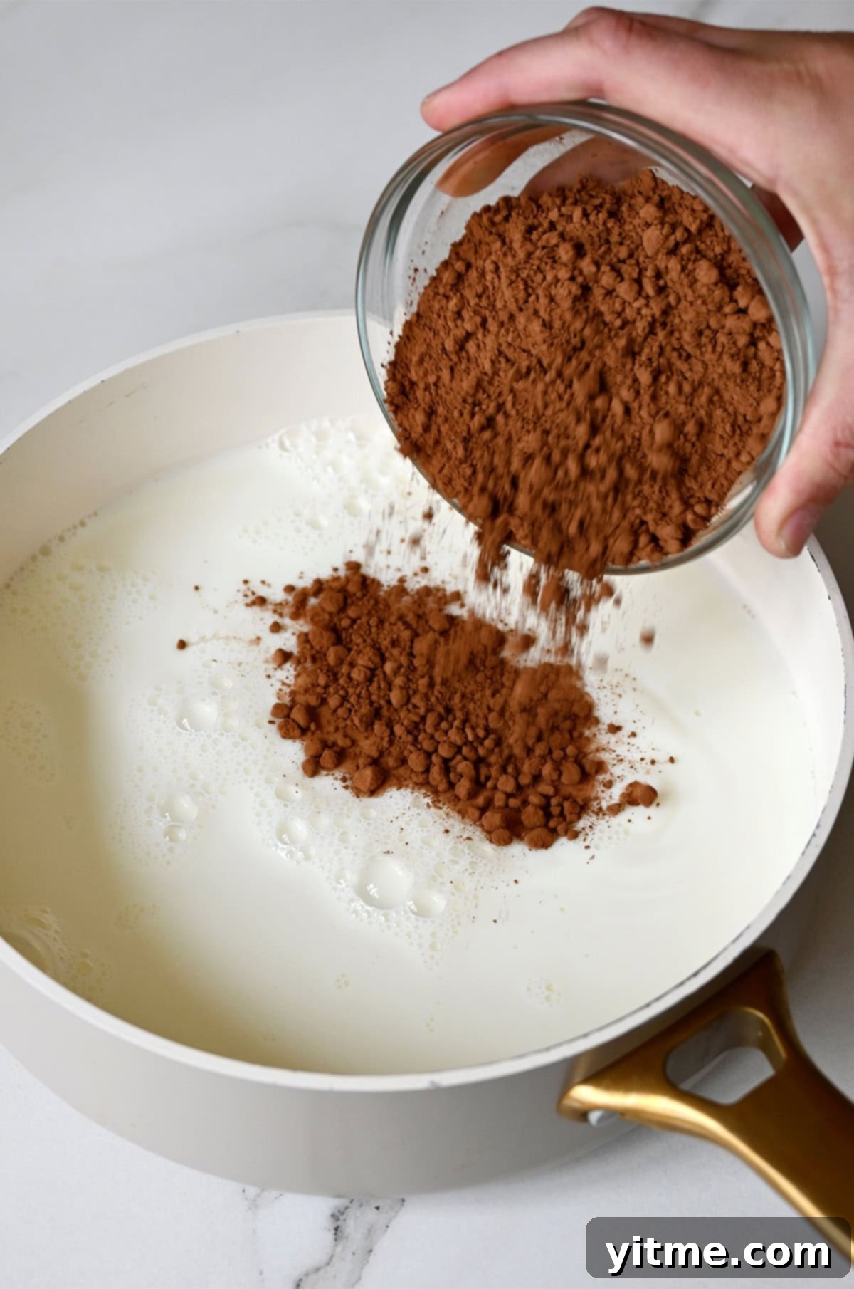 Adding unsweetened cocoa powder to a saucepan filled with milk, sugar, corn syrup, and salt.