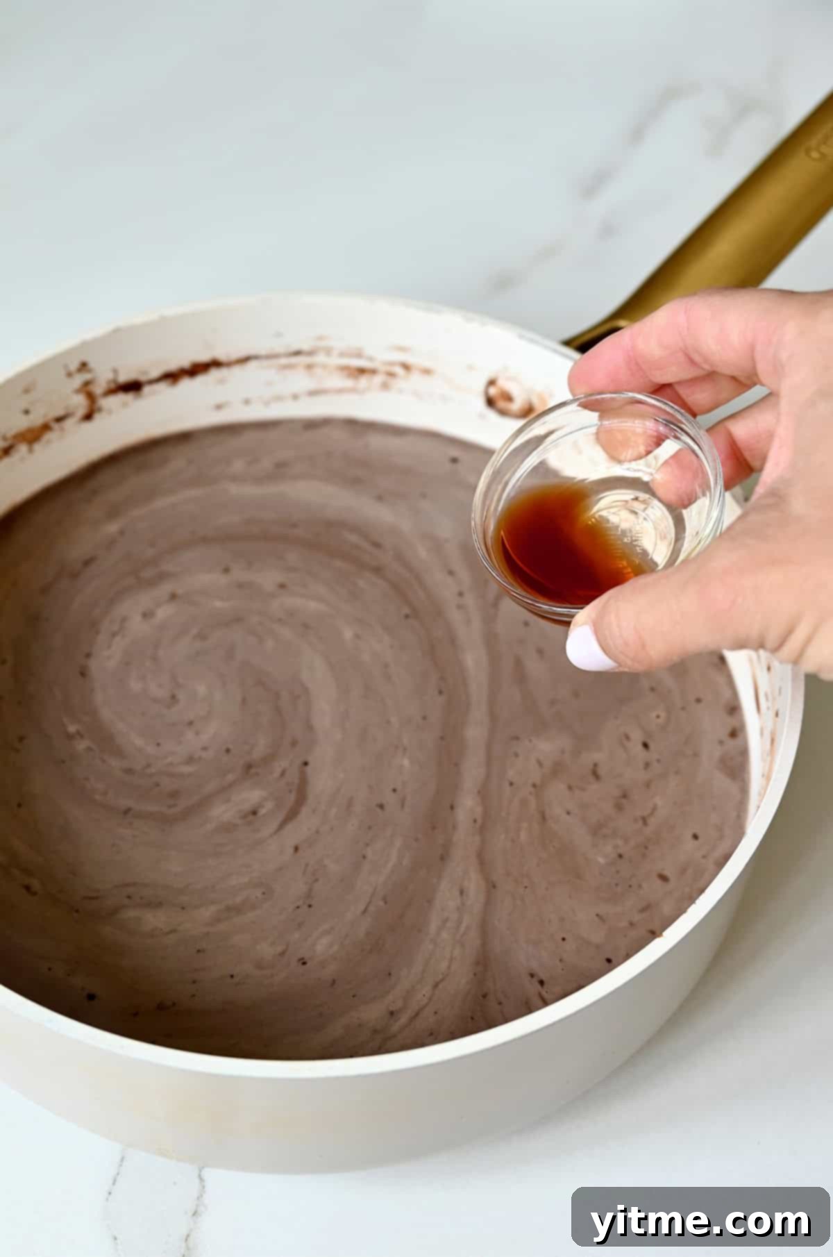 Stirring vanilla extract into the warm chocolate milk mixture in a saucepan off the heat.