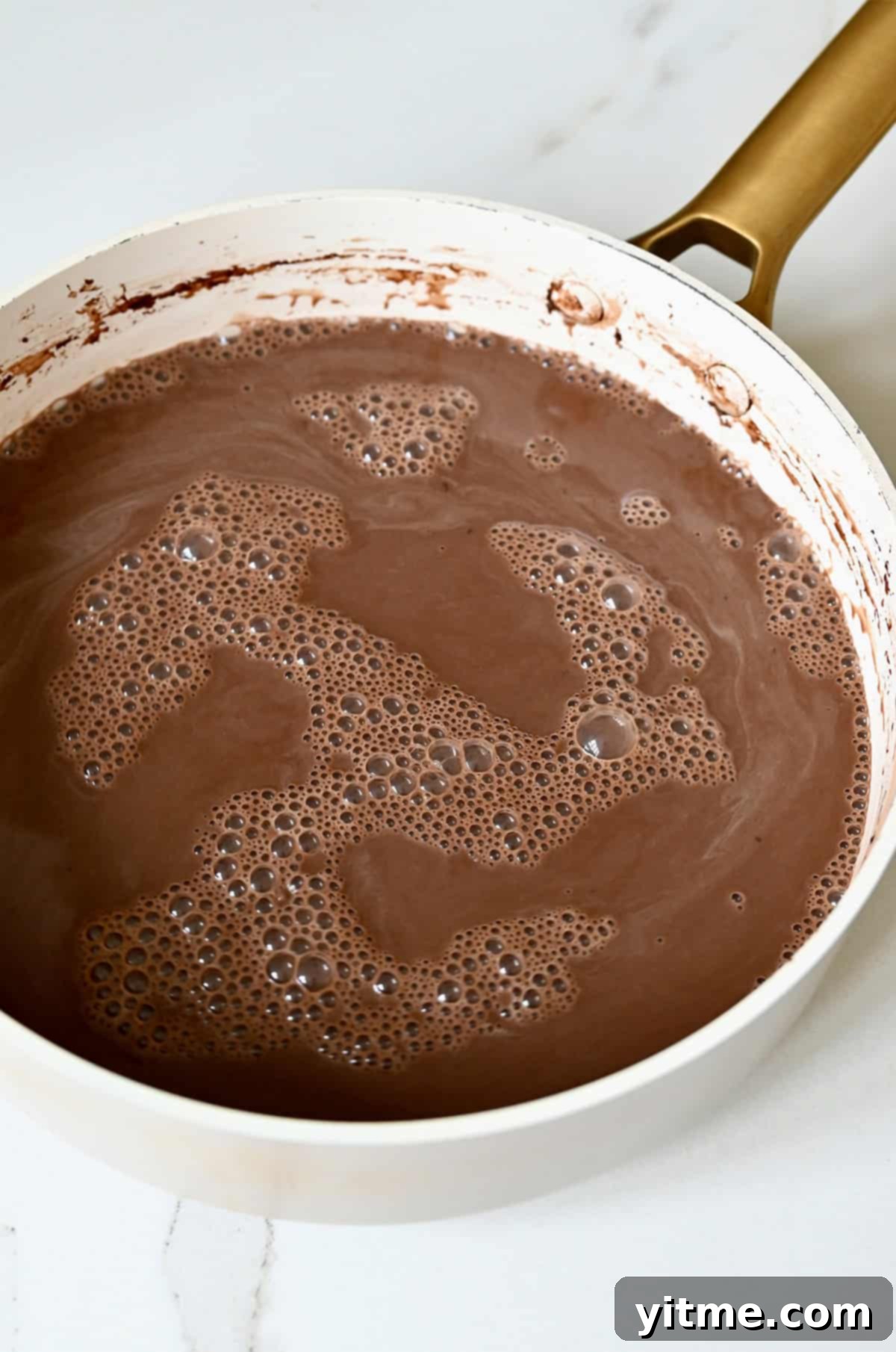 A rich, dark chocolate popsicle mixture resting in a saucepan, ready for cooling.