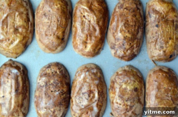 Baked, scooped out potatoes cut side down on a baking sheet.