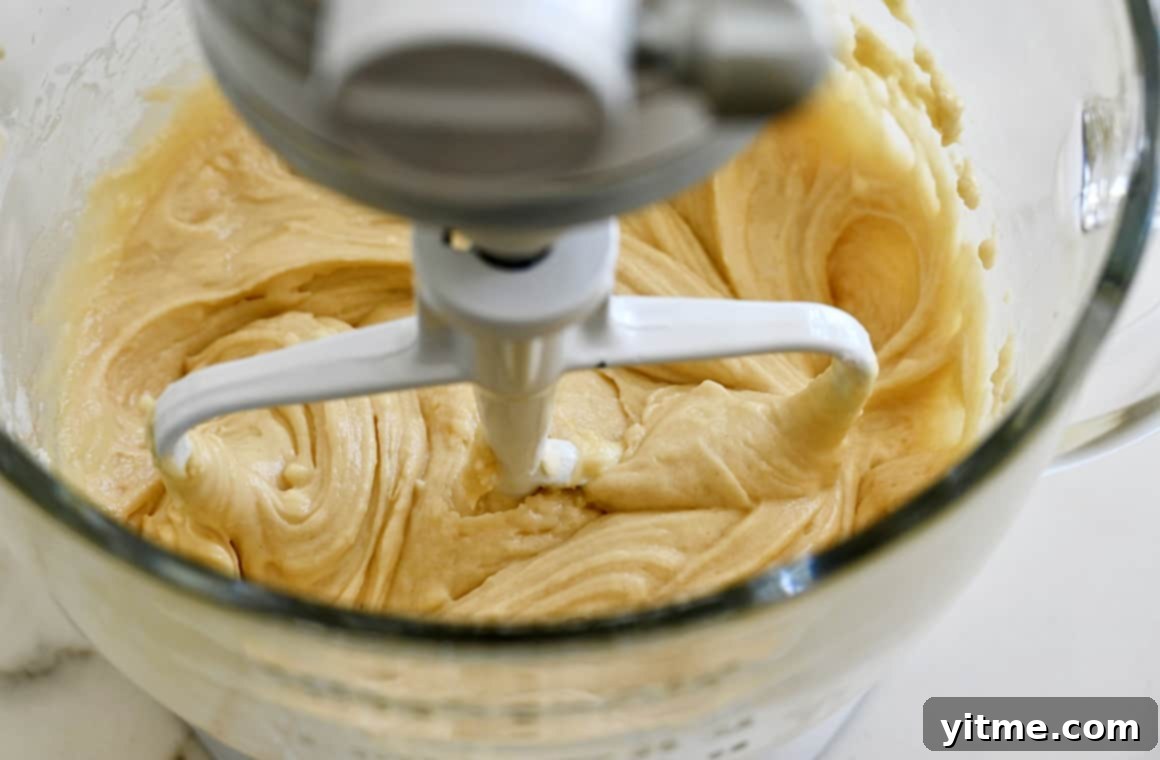 A clear stand mixer bowl containing batter.
