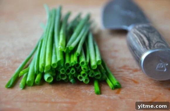 Freshly chopped chives, a key ingredient for savory popovers, scattered on a cutting board.