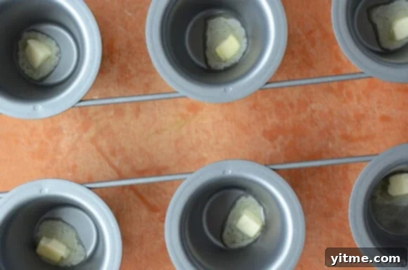 Melted butter shimmering at the bottom of a popover pan, preparing for the batter.