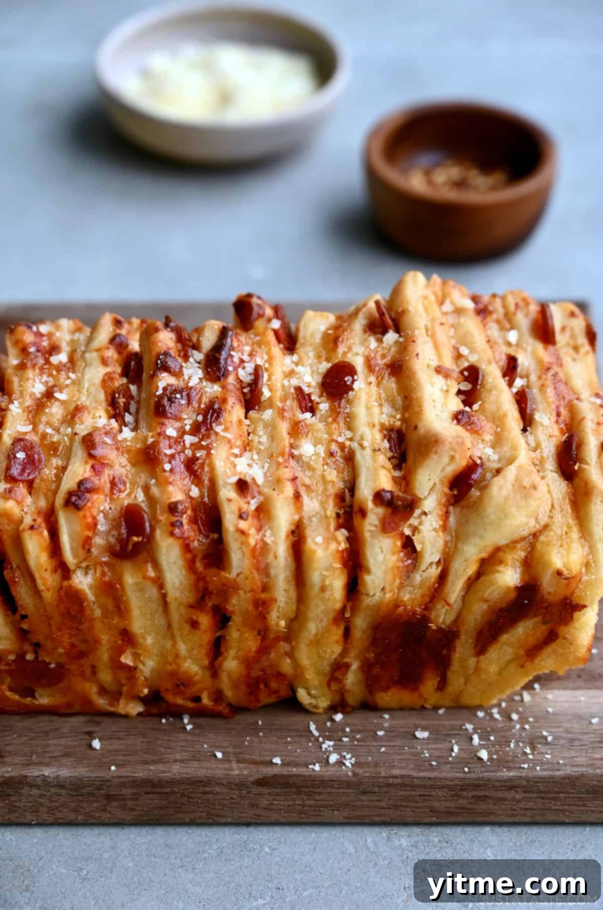Pizza pull-apart bread with mini pepperoni garnished with grated parmesan cheese on a cutting board.