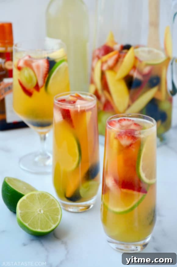 Various glasses filled with the best homemade white sangria with strawberries, limes, apples, grapes, blackberries and peaches