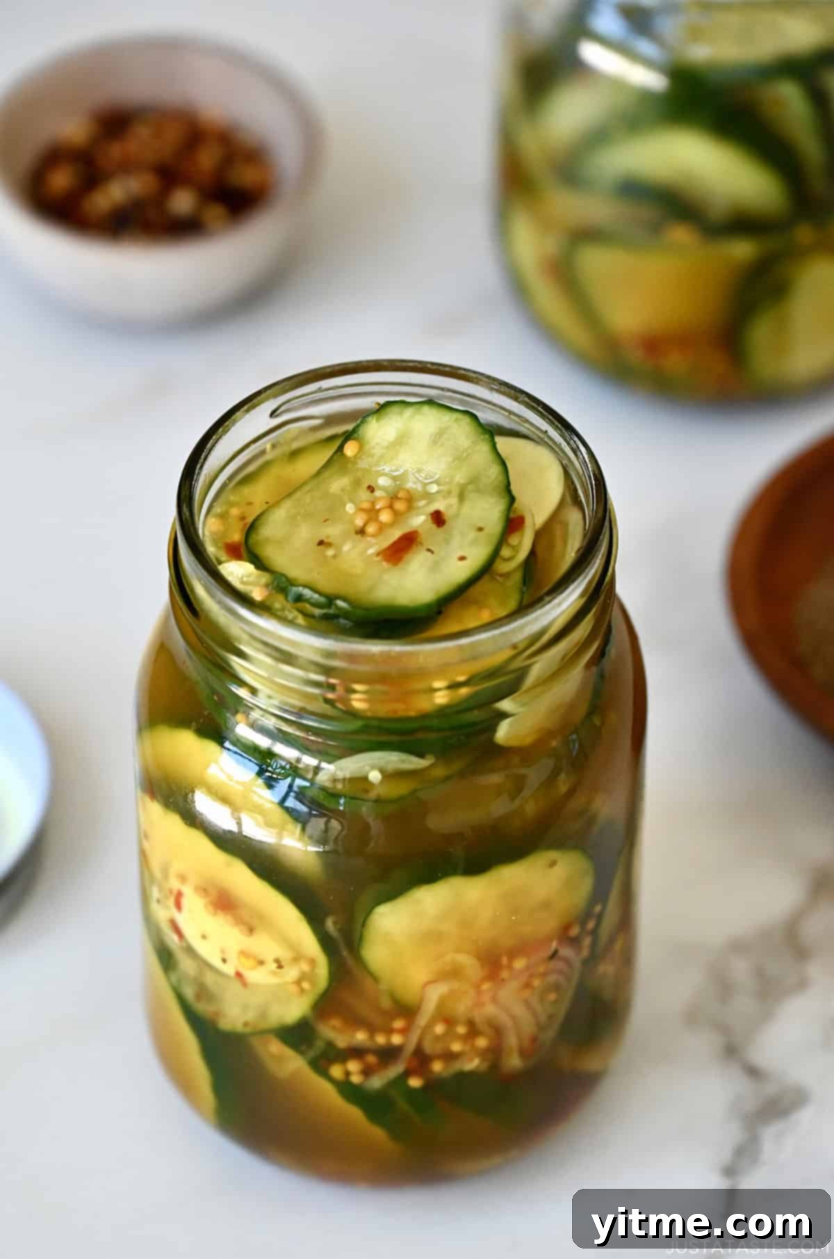 A glass pint jar filled to the brim with homemade bread and butter pickles.