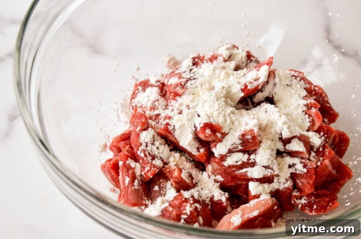 Thin slices of flank steak covered in cornstarch in a bowl.