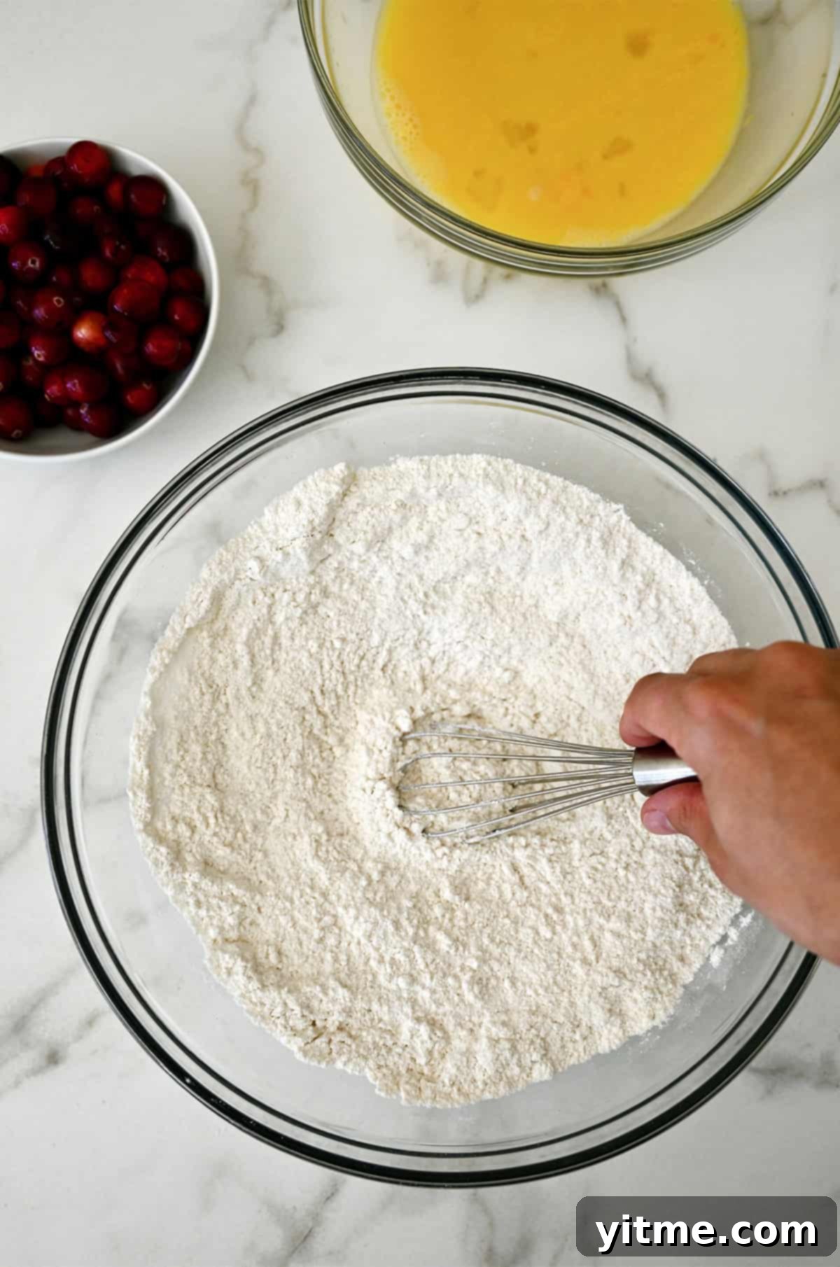 Dry ingredients for cranberry orange bread in a large glass bowl, whisked together.