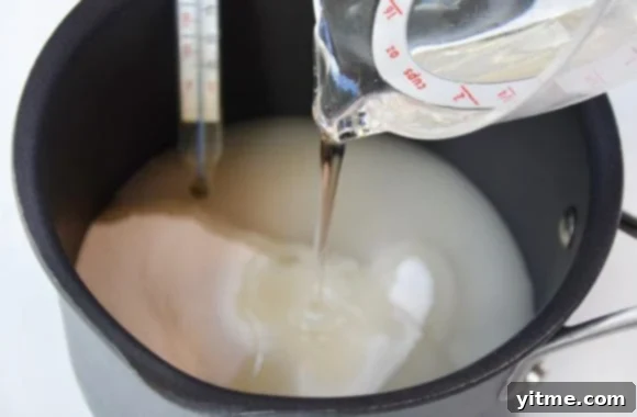 Saucepan containing sugar and corn syrup with candy thermometer