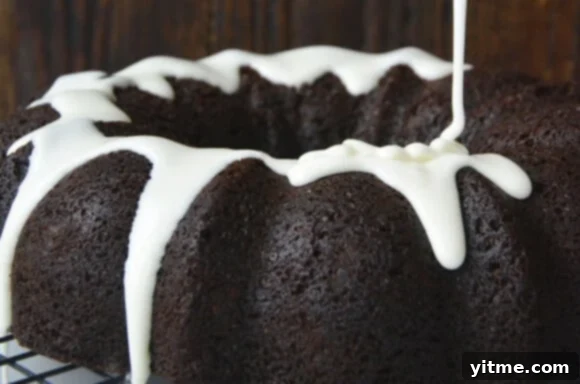 Vanilla glaze being drizzled over chocolate gingerbread bundt cake