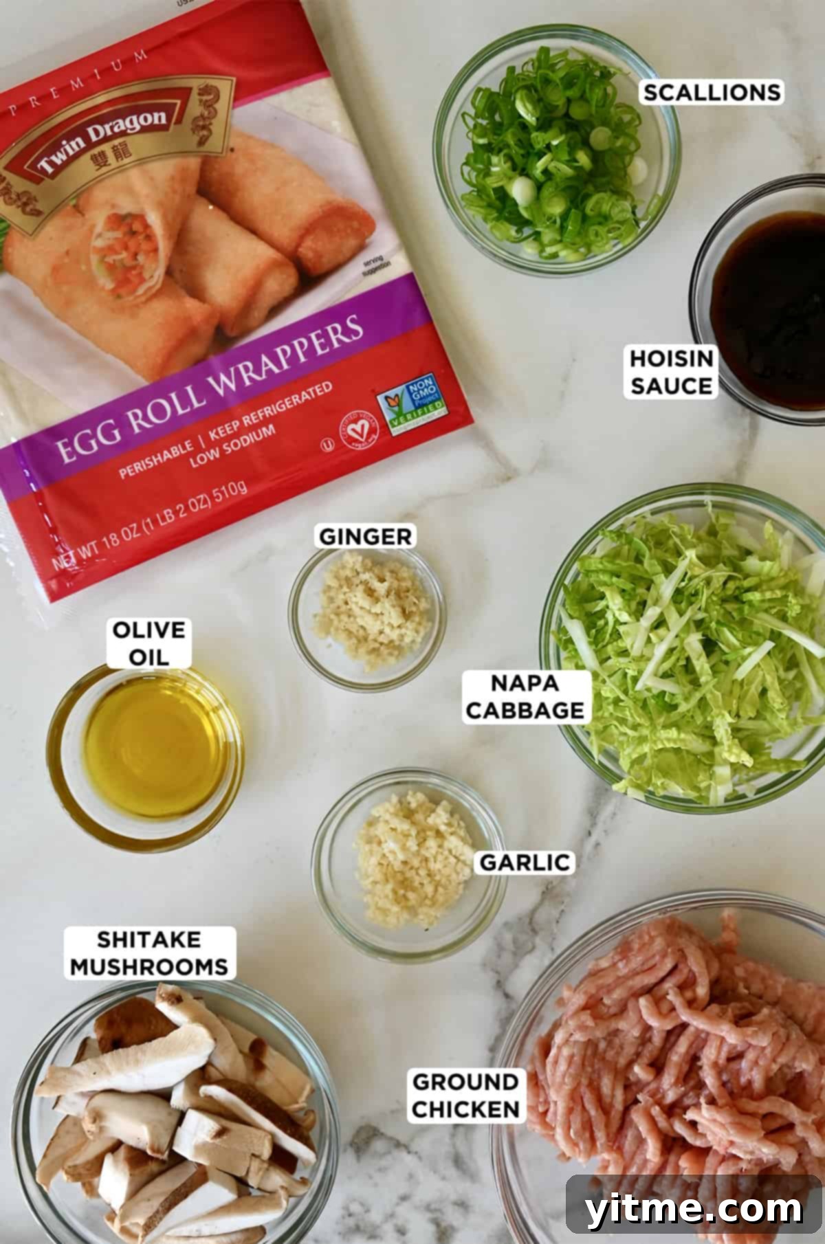 Ingredients for chicken spring rolls, including ground chicken, cabbage, mushrooms, ginger, garlic and spring roll wrappers.