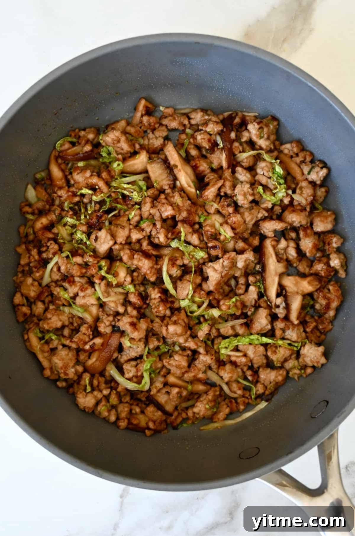 Sautéed chicken, cabbage, and mushrooms in a skillet for chicken spring rolls.