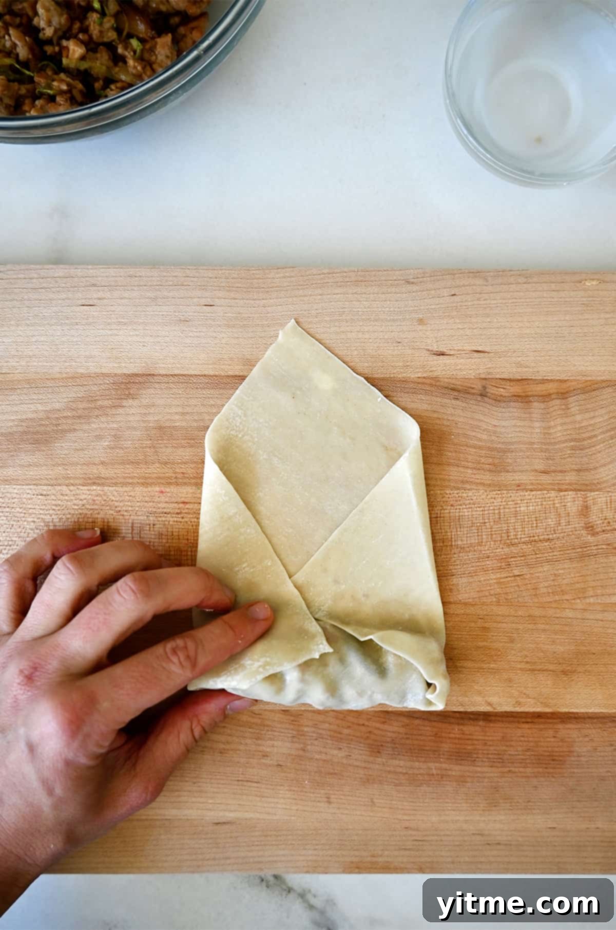 Folding in the sides of the spring roll wrapper.