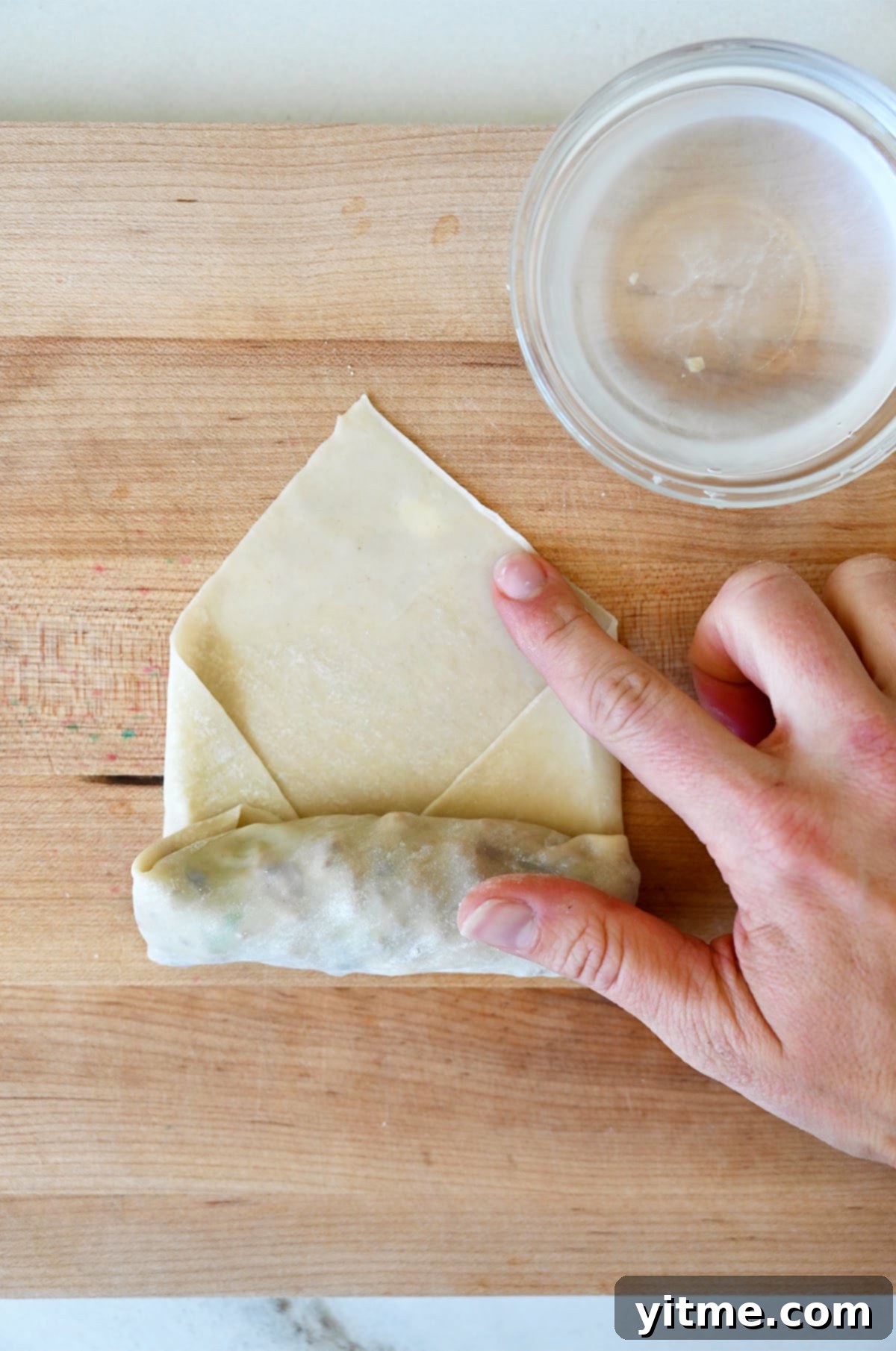 Rolling up the spring roll and sealing the edge.