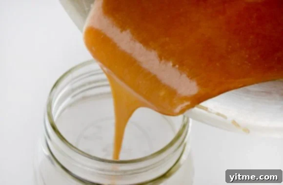 Pouring Easy Homemade Butterscotch Sauce into a mason jar