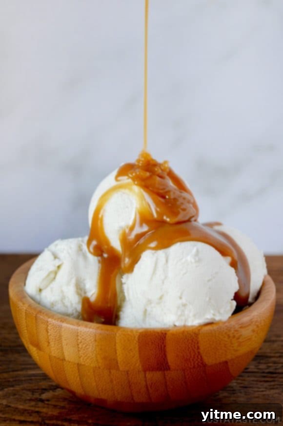 Easy Homemade Butterscotch Sauce poured over vanilla ice cream in wooden bowl