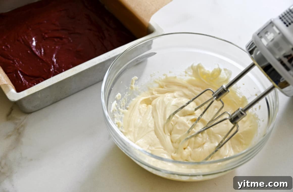 Cheesecake mixture in a clear bowl being mixed with a hand beater