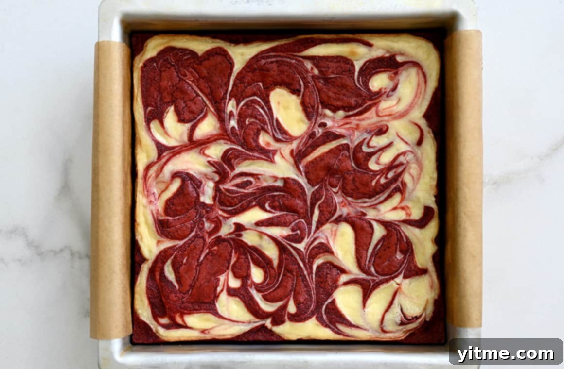 Baked red velvet brownies in a parchment paper-lined pan