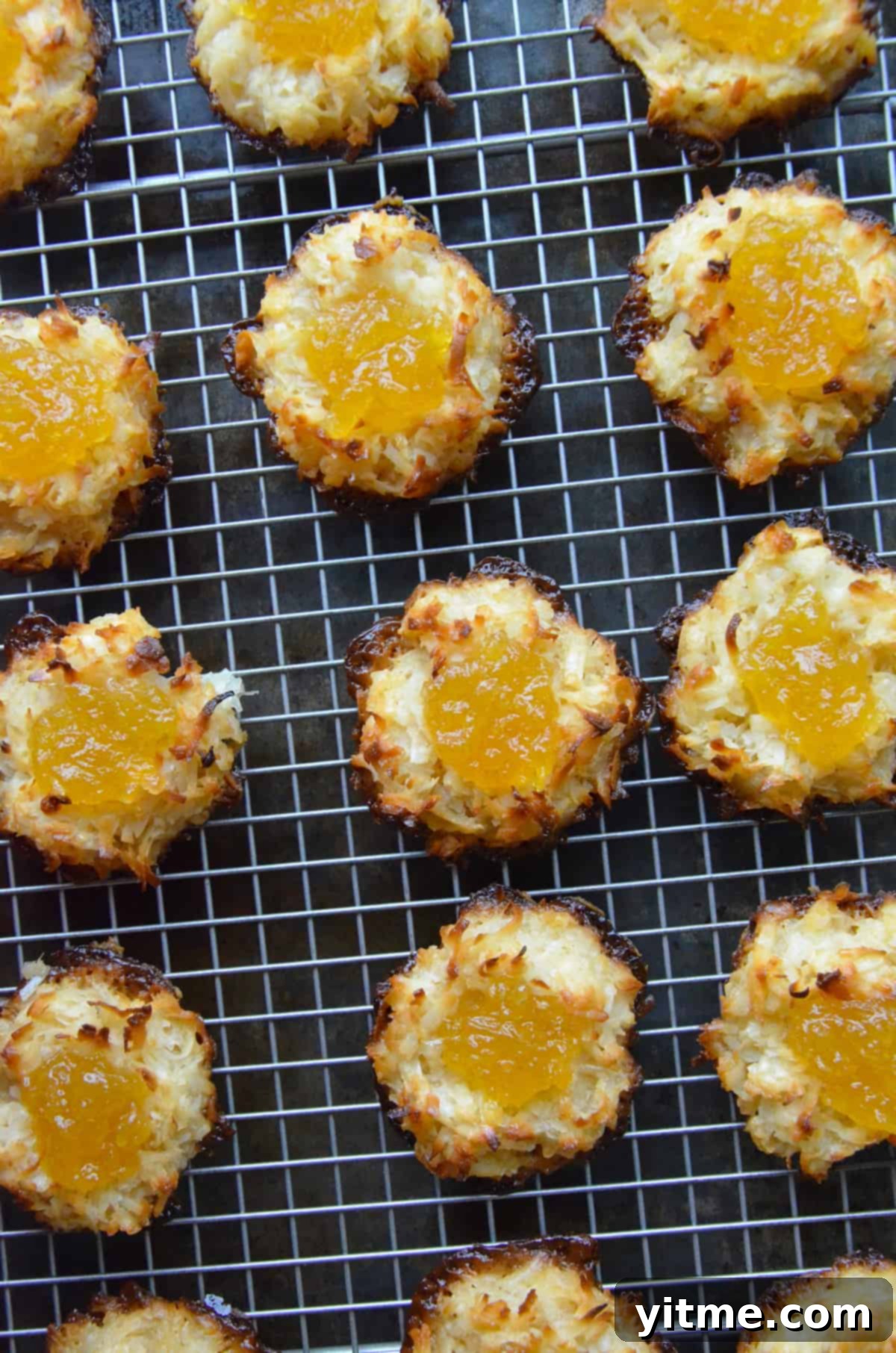 Coconut macaroons filled with pineapple jam arranged on a cooling rack