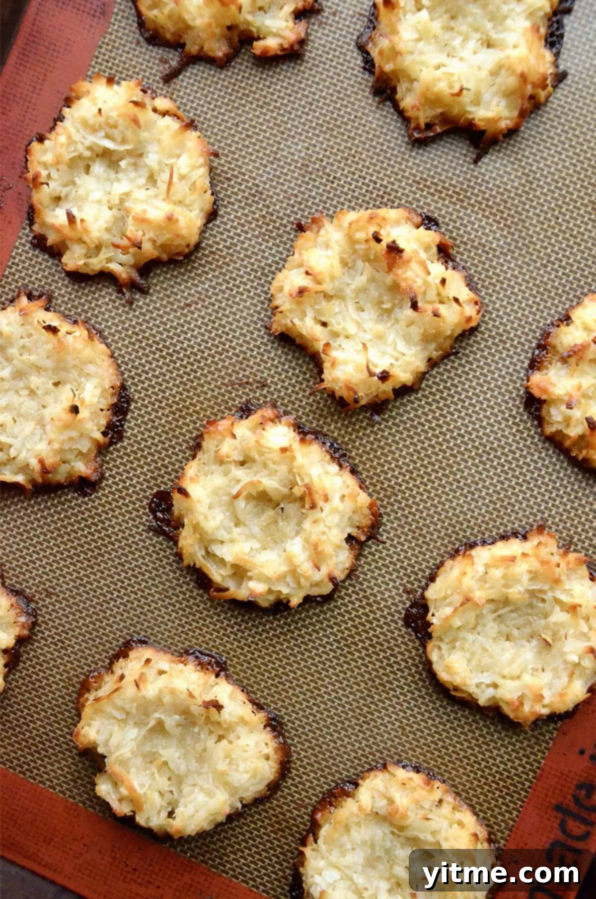 Baked coconut macaroon nests cool on a Silpat baking sheet.