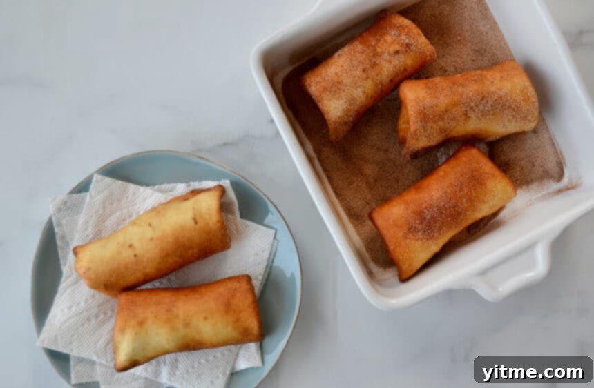 Deep-fried tortillas in a shallow dish being rolled in a cinnamon-sugar mixture