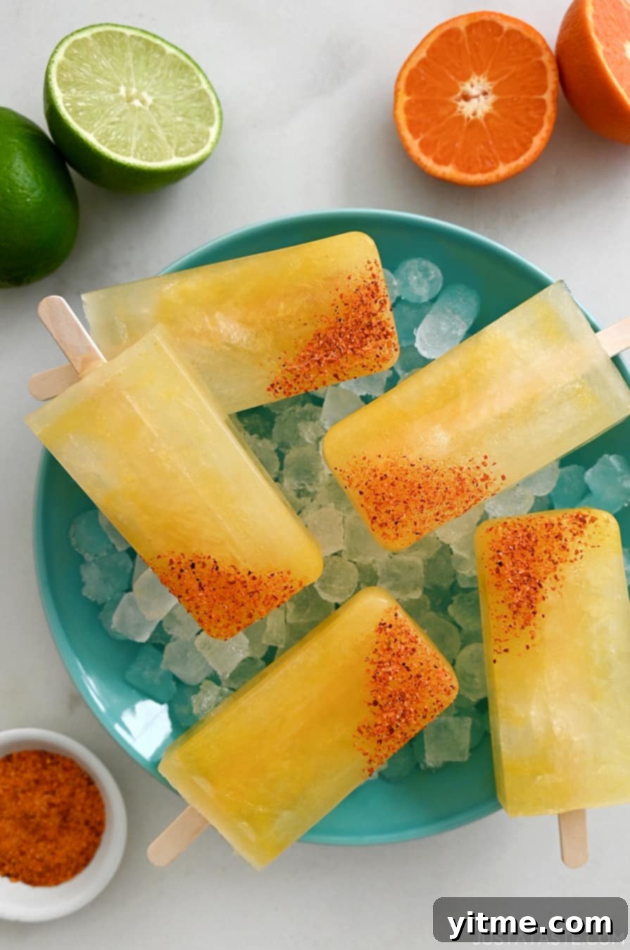 Skinny Margarita Popsicles dipped in tajin seasoning over ice with lime and orange