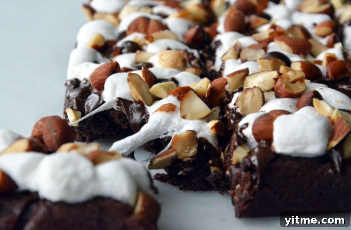 Rocky road brownies topped with chopped almonds. A corner of the brownies is pulled off.