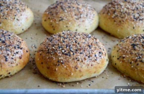 Baked burger buns on a baking sheet, sprinkled with everything bagel seasoning