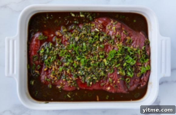 Flank steak in Asian marinade topped with minced garlic and ginger, and thinly sliced scallions