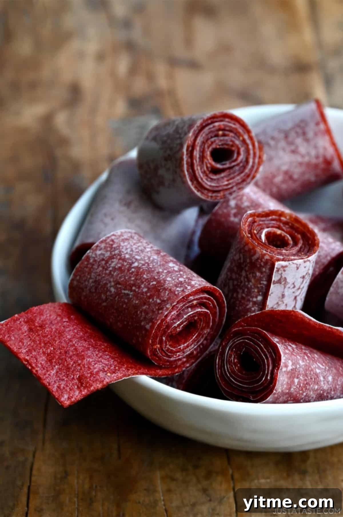 Homemade strawberry fruit roll-ups in a white bowl.