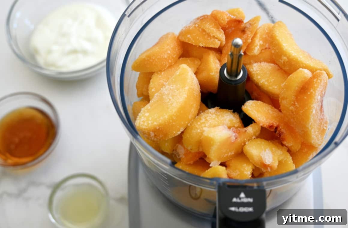 Frozen peaches in a food processor bowl next to small bowls containing plain yogurt, honey, and lemon juice – the simple ingredients for homemade froyo.