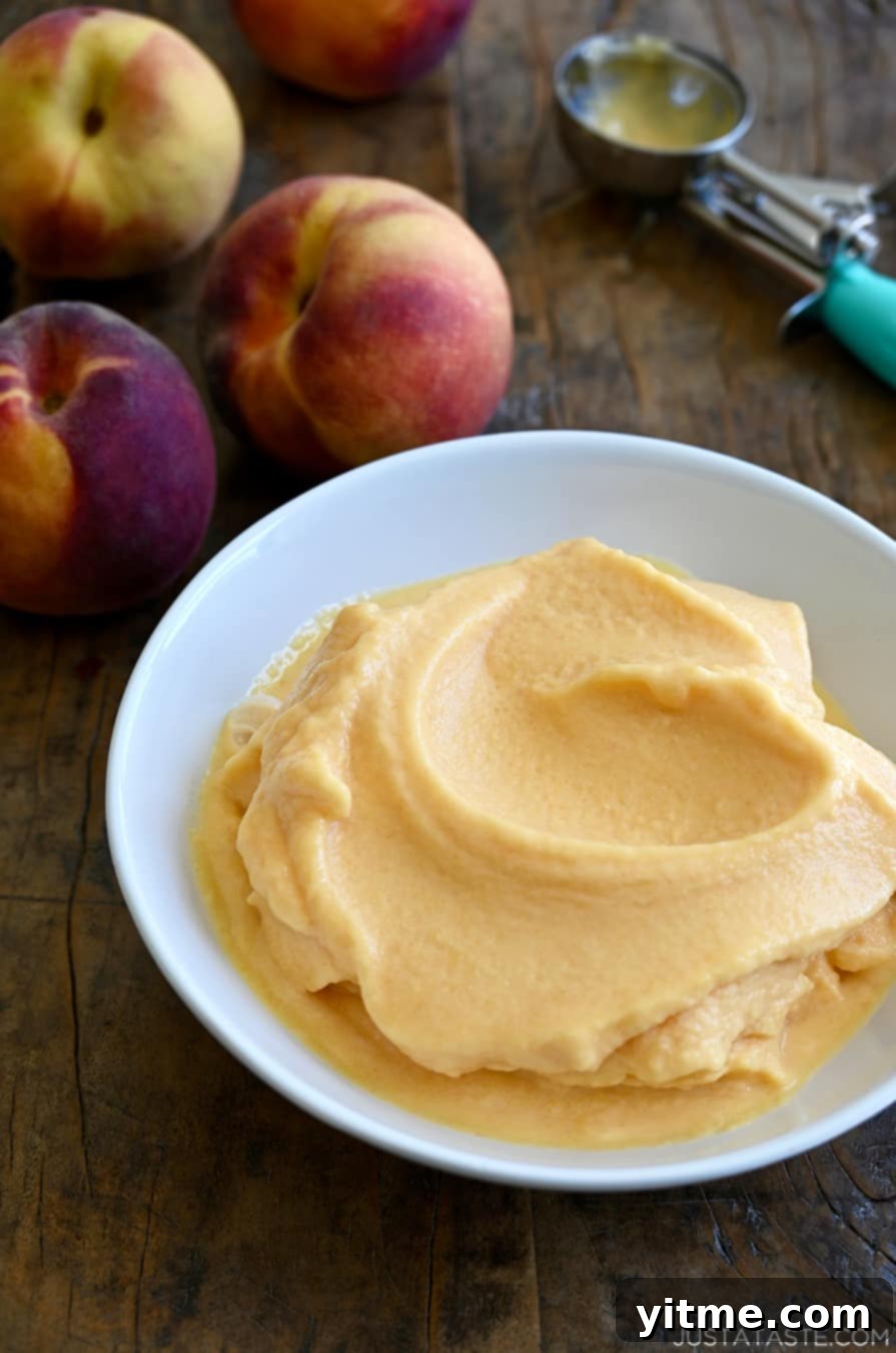 Cool and creamy 5-Minute Healthy Peach Frozen Yogurt in a white bowl next to fresh peaches, perfect for a quick and nutritious dessert.
