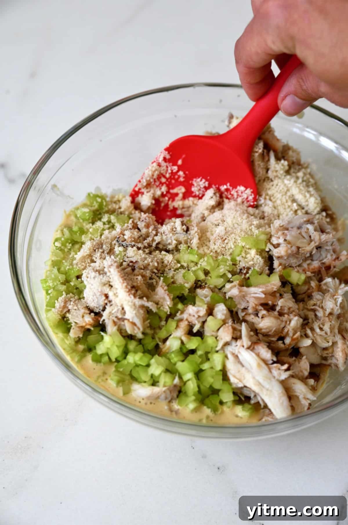 Lump crab meat with celery and Panko breadcrumbs in a bowl for making crab cakes.