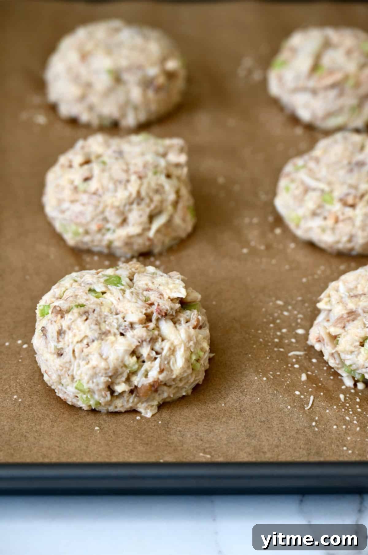 Shaped crab cakes on parchment paper.