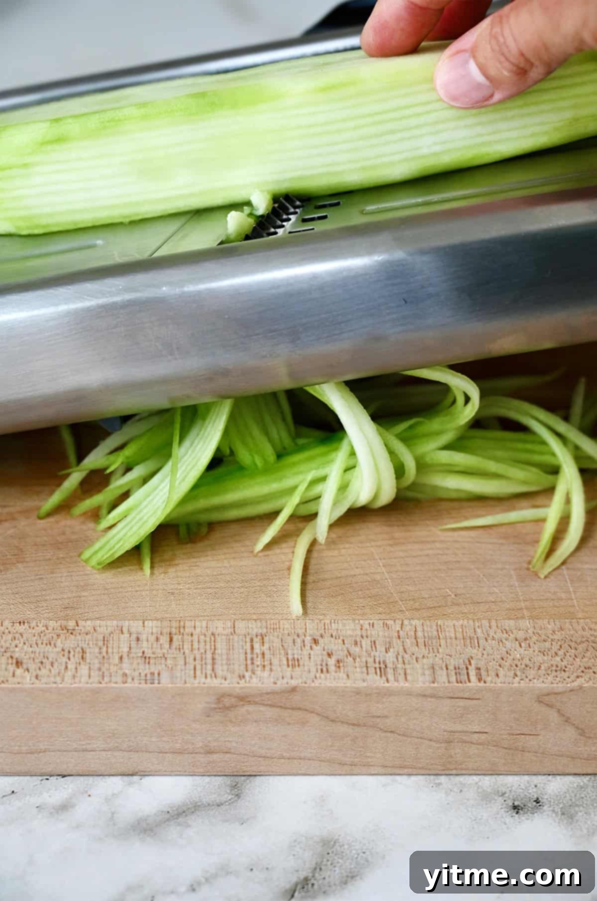 Making cucumber noodles using a mandoline.