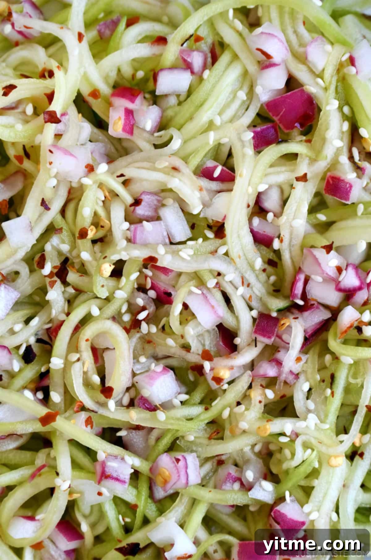 Sweet and sour cucumber salad with diced red onions and sesame seeds.