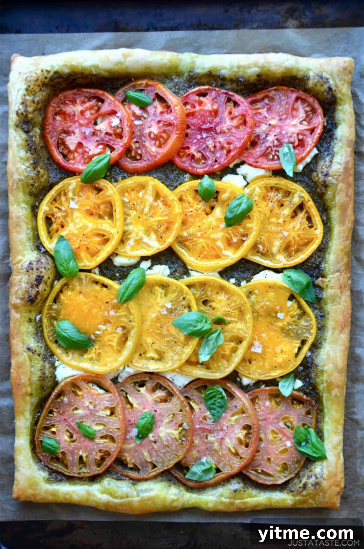 A beautifully baked heirloom tomato and goat cheese tart, garnished with fresh basil leaves.