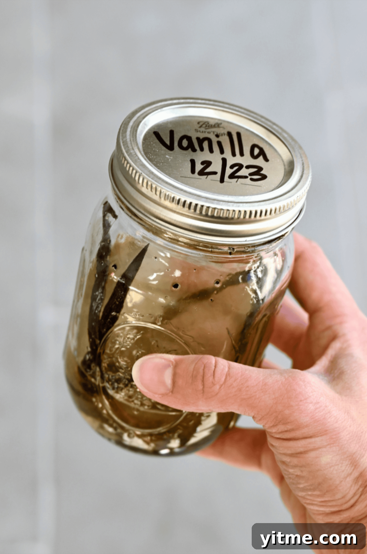 Craft Your Own Vanilla Extract 5 Vanilla bean pods and vodka in a mason jar labeled "Vanilla 12/23."