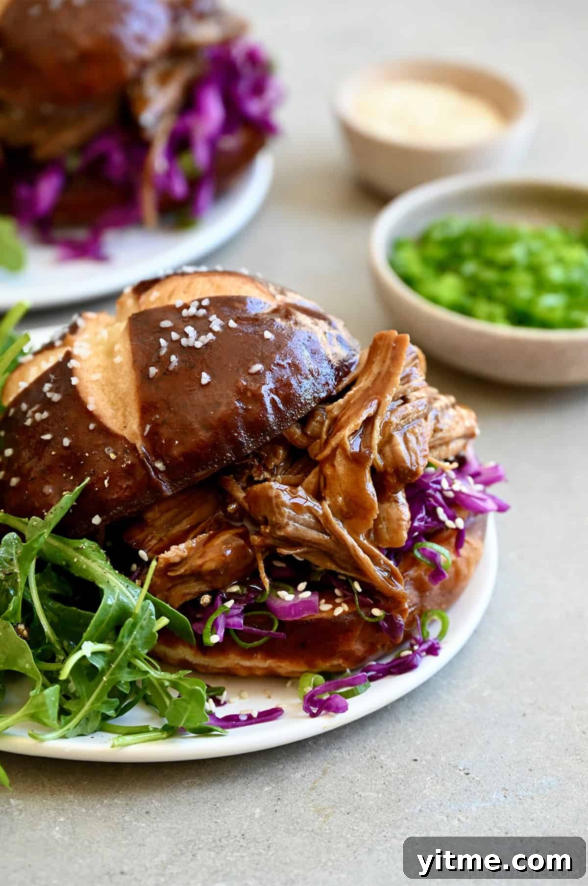 Balsamic Honey Pulled Pork: A Slow Cooker Delight 2 Balsamic honey pulled pork sandwich on a plate with arugula.