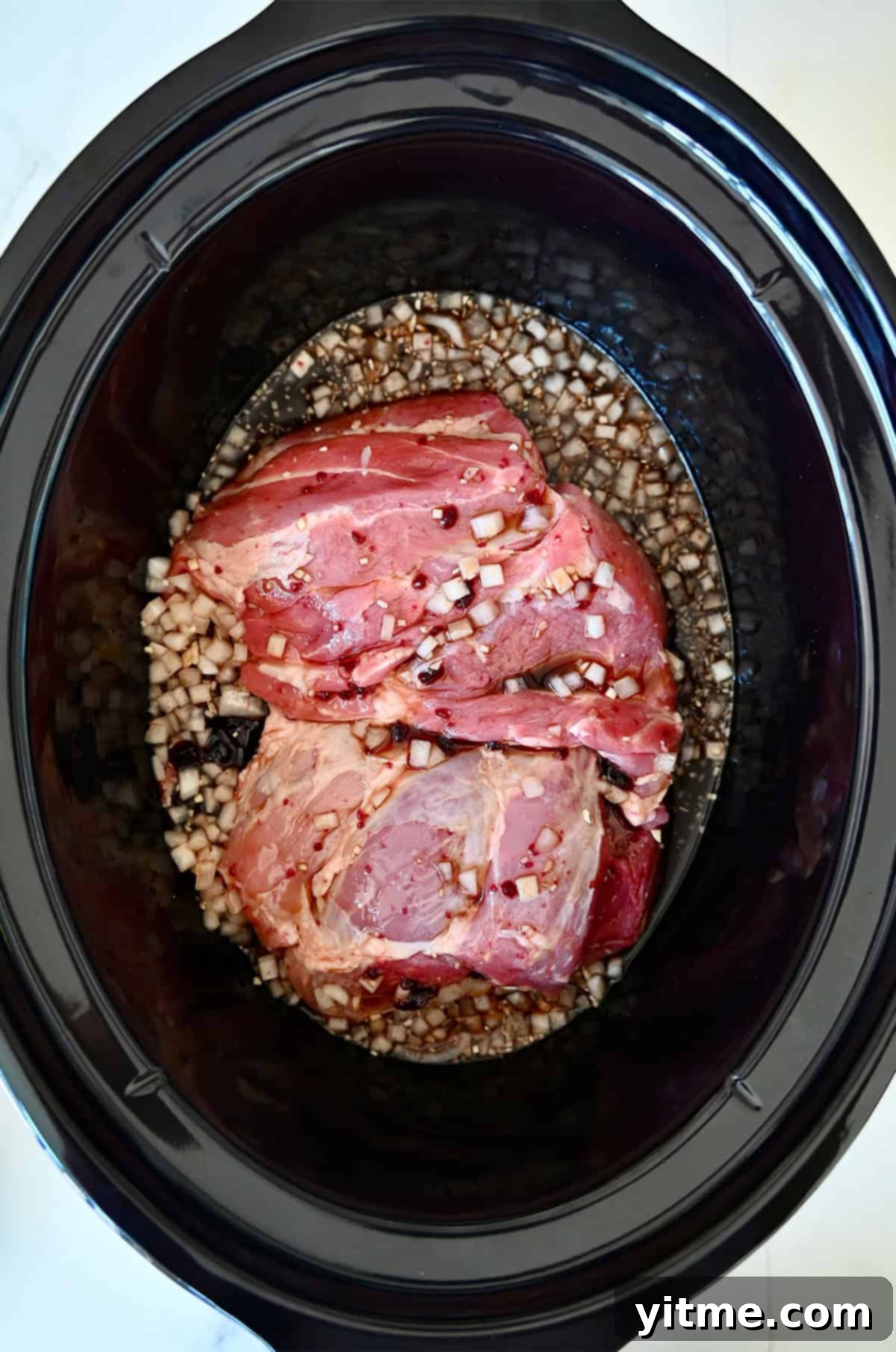 Balsamic Honey Pulled Pork: A Slow Cooker Delight 5 Boneless pork shoulder in a slow cooker covered with cooking liquid.