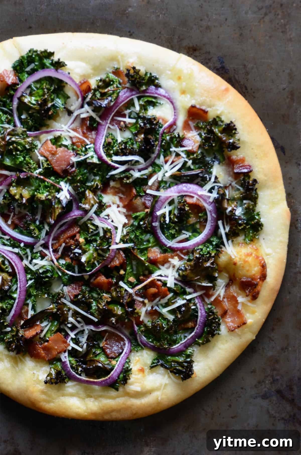 Garlic-Kissed Kale & Bacon Pie 7 Kale and bacon pizza topped with grated parmesan cheese and red onion slices.