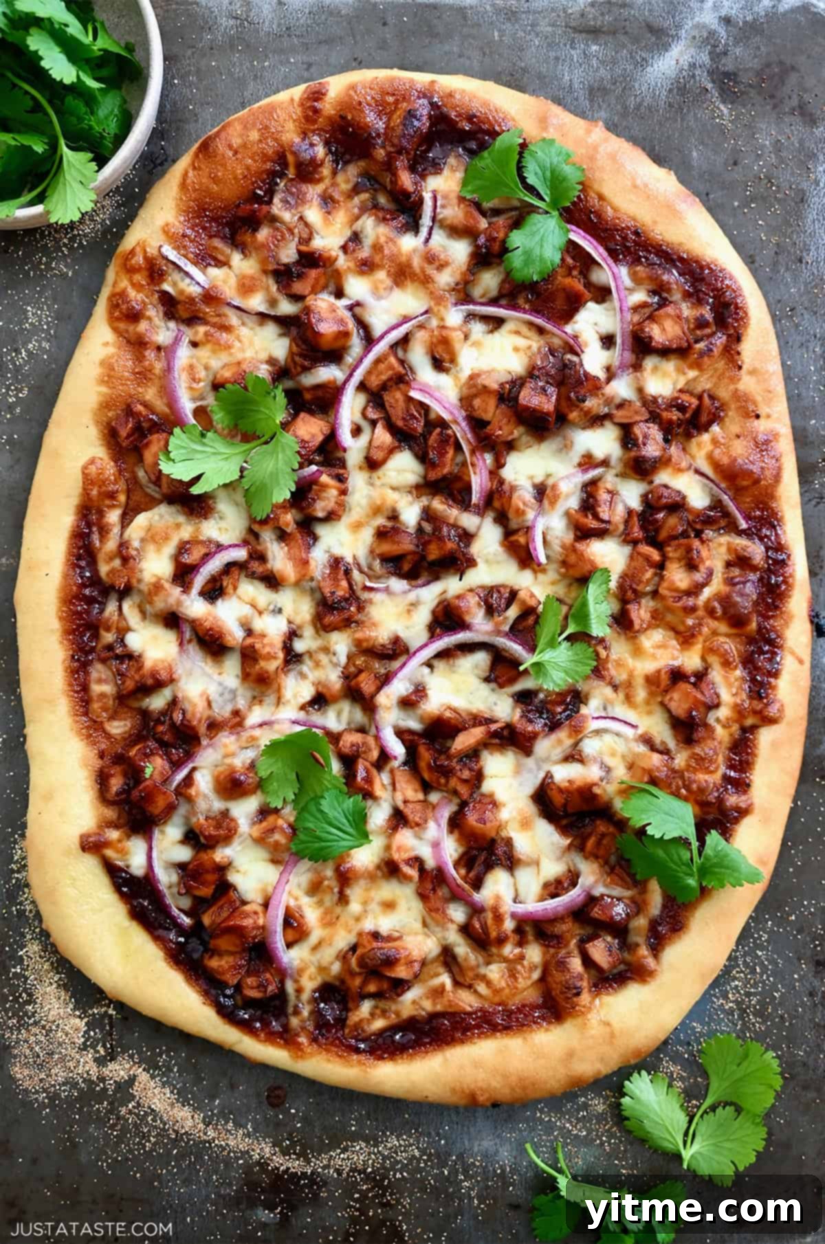 Delicious BBQ chicken pizza with barbecue sauce, red onion, shredded chicken, mozzarella cheese, and fresh cilantro.