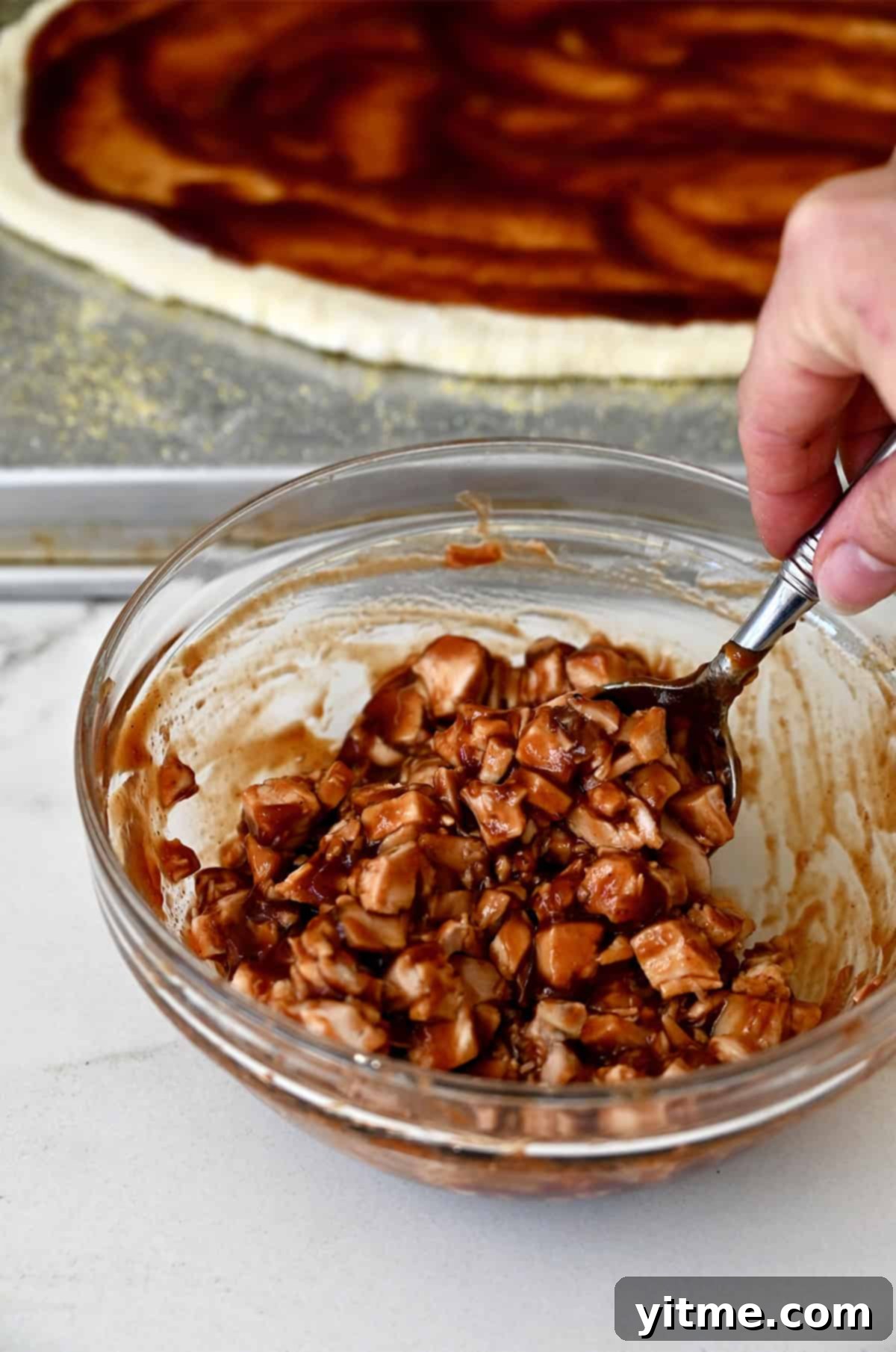 Coating diced chicken in bbq sauce in a bowl.